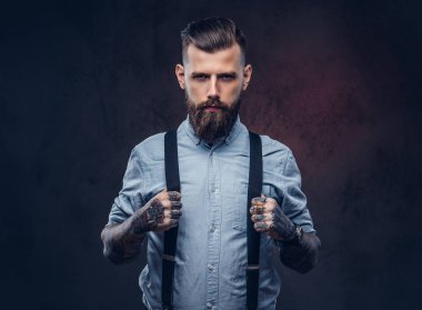 Mavi bir gömlek ve pantolon askısı yakışıklı bir eski moda hipster portresi. Karanlık bir arka plan üzerinde izole.