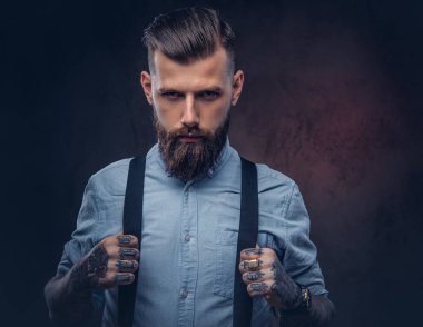 Mavi bir gömlek ve pantolon askısı yakışıklı bir eski moda hipster portresi. Karanlık bir arka plan üzerinde izole.