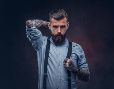 Mavi bir gömlek ve pantolon askısı yakışıklı bir eski moda hipster portresi. Karanlık bir arka plan üzerinde izole.