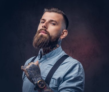 Mavi bir gömlek ve pantolon askısı yakışıklı bir eski moda hipster portresi. Karanlık bir arka plan üzerinde izole.