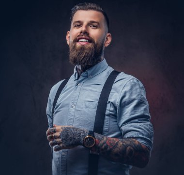 Mavi bir gömlek ve pantolon askısı gülümseyen yakışıklı eski moda hipster portresi. Karanlık bir arka plan üzerinde izole.