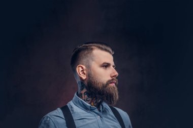 Mavi bir gömlek ve pantolon askısı yakışıklı bir eski moda hipster profil. Karanlık bir arka plan üzerinde izole.