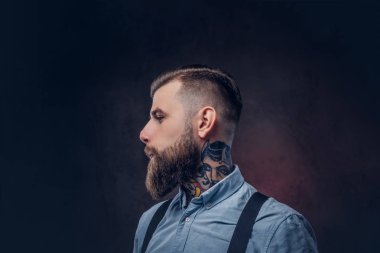 Mavi bir gömlek ve pantolon askısı yakışıklı bir eski moda hipster profil. Karanlık bir arka plan üzerinde izole.