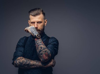 Dalgın yakışıklı eski moda hipster gömlek ve pantolon askısı, çene üzerinde el ile poz. Karanlık bir arka plan üzerinde izole.