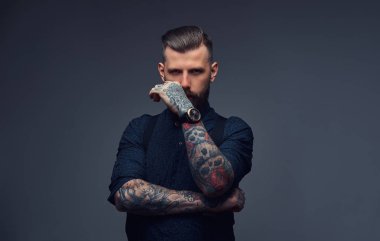 Dalgın yakışıklı eski moda hipster gömlek ve pantolon askısı, çene üzerinde el ile poz. Karanlık bir arka plan üzerinde izole.