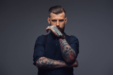 Dalgın yakışıklı eski moda hipster gömlek ve pantolon askısı, çene üzerinde el ile poz. Karanlık bir arka plan üzerinde izole.