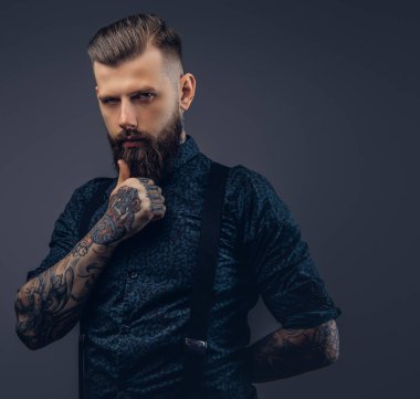 Dalgın yakışıklı eski moda hipster gömlek ve pantolon askısı, çene üzerinde el ile poz. Karanlık bir arka plan üzerinde izole.