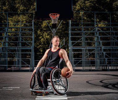 Açık oyun zeminde tekerlekli sandalyede bir Engelli basketbol oyuncusu portresi.