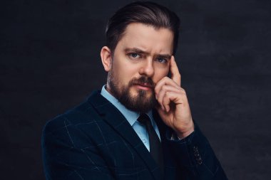 Sakal ve saç modeli ile dalgın orta yaşlı adam Studio dokulu koyu arka plan üzerinde zarif bir mavi elbise giymiş.