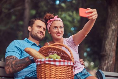 Çekici çift açık havada kalma sırasında selfie bir piknik bir parkta alarak gülümseyen.