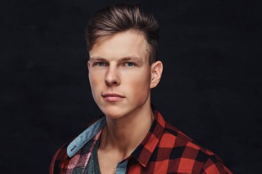 Yakın çekim yakışıklı bir genç adam bir stüdyoda poz bir yün gömlekli portresi. Karanlık bir arka plan üzerinde izole