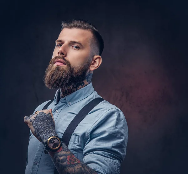 Mavi bir gömlek ve pantolon askısı yakışıklı bir eski moda hipster portresi. Karanlık bir arka plan üzerinde izole.