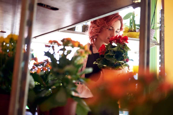 Güzel kızıl saçlı kadın çiçekçi giyen üniforma çiçekçide çalışan.