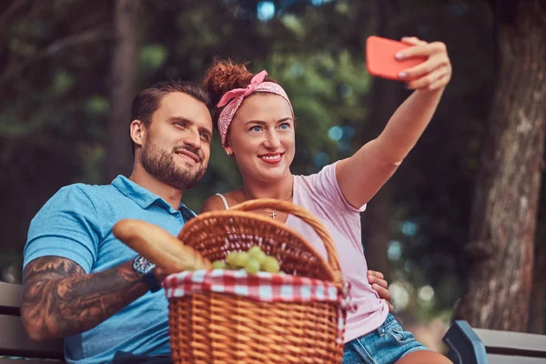 Çekici çift açık havada kalma sırasında selfie bir piknik bir parkta alarak gülümseyen.