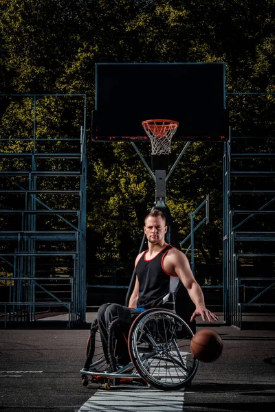 Joueur de basket-ball cramoisi dans un fauteuil roulant joue sur un terrain de jeu ouvert . — Photo
