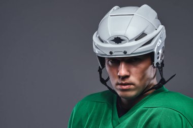 Yakın çekim portre profesyonel hokey oyuncusu bir koruyucu spor giyim ve kask. Gri bir arka plan üzerinde izole.