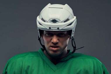 Yakın çekim portre bir koruyucu spor giyim ve kask bir öfkeli profesyonel hokey oyuncusu. Gri bir arka plan üzerinde izole.