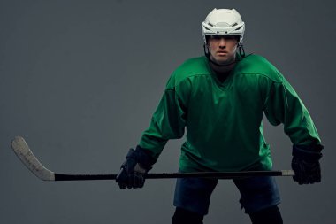 Tam dişli ve hokey sopası giyen profesyonel hokey oyuncusu portresi. Gri bir arka plan üzerinde izole.