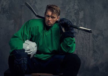 Ahşap palet üzerinde oturan sert bir çalışmadan sonra profesyonel hokey oyuncusu aittir. Gri bir arka plan üzerinde izole.