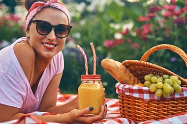 Bir kafa bandı ve açık havada yatarken üzerinde bir battaniyeye bir park piknik sırasında zevk güneş gözlüğü ile rahat kıyafetler içinde mutlu kızıl saçlı orta yaş kadın.
