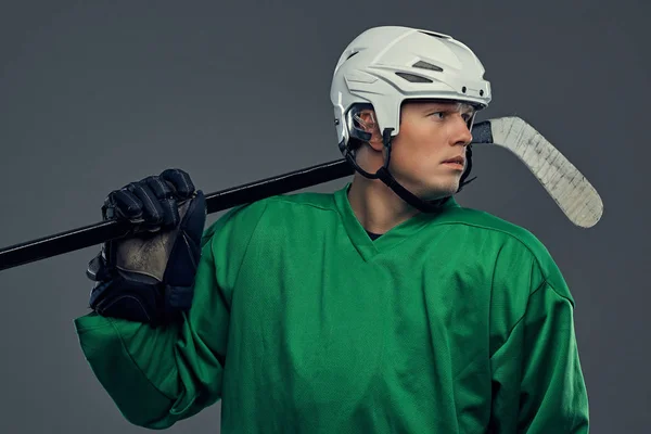 Profesionální hokejista v plné vybavení s herní holí na ramenou na šedém pozadí. — Stock fotografie