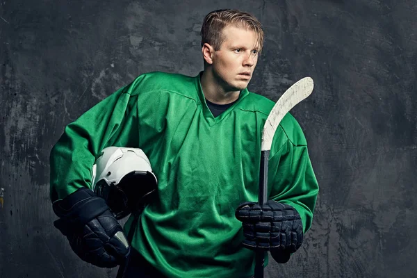 Trött Professionell Ishockeyspelare Grön Sportkläder Innehar Hockeyklubba Och Skyddshjälm Isolerad — Stockfoto