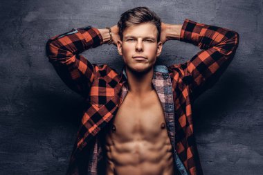 Bir stüdyoda poz açılarak Polar gömlek ile seksi bir adam. Karanlık bir arka plan üzerinde izole.