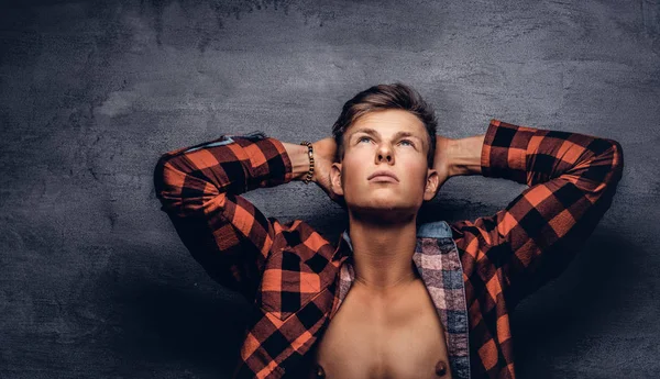 Sexy guy with unbuttoned fleece shirt posing at a studio. Isolated on a dark background.