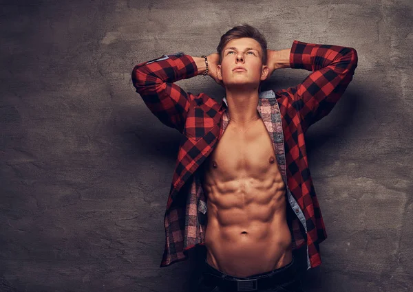 Sexy guy with unbuttoned fleece shirt posing at a studio. Isolated on a dark background.