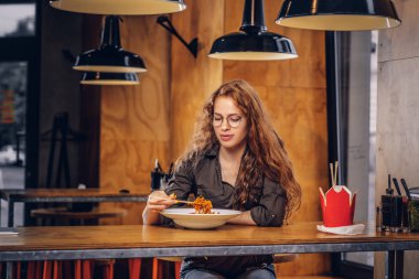 Baharatlı Erişte Asya bir restoranda yemek rahat kıyafetler giymiş akıllı genç Kızıl saçlı erkek. 