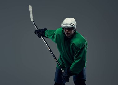 Profesyonel hokey oyuncusu trenler tam ekipman oyun sopa ile. Gri bir arka plan üzerinde izole.