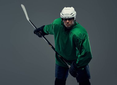 Profesyonel hokey oyuncusu trenler tam ekipman oyun sopa ile. Gri bir arka plan üzerinde izole.