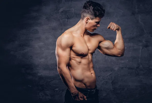 強靭な上半身裸の若者の素敵な筋肉ボディ スタジオで彼の力こぶを示すモデル 暗い背景に分離 — ストック写真