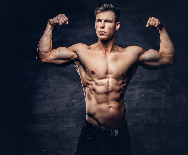 強靭な上半身裸の若者の素敵な筋肉ボディ スタジオで彼の力こぶを示すモデル 暗い背景に分離 — ストック写真