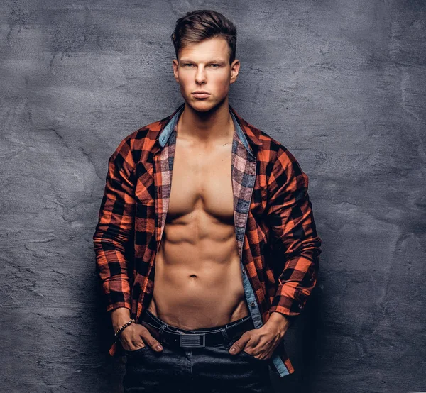 Bir stüdyoda poz açılarak Polar gömlek ile seksi bir adam. Karanlık bir arka plan üzerinde izole.