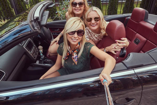 三愉快的时尚女性朋友采取自拍相片在豪华敞篷车汽车 在他们的夏天旅行假期期间 — 图库照片