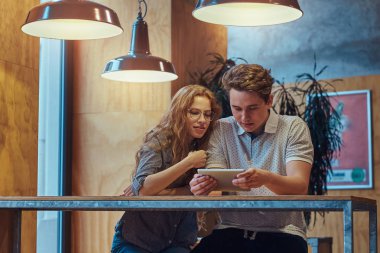 Düşünceli genç çift öğrenci üniversite kantin bir masada oturan bir mola sırasında dijital tablet kullanma.