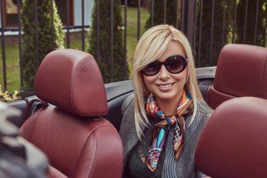 Mutlu güzellik sarışın kadın elbise ve gezi tatil bir Cabrio araba arka koltukta oturan gri deri ceket giyen güneş gözlüğü.