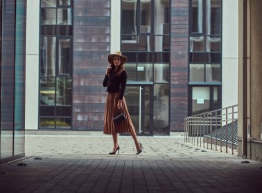 Avrupa şehir merkezine yürüyüş bir el çantası debriyaj ile bir siyah ceket, kahverengi şapka ve etek giyen moda zarif kadın.