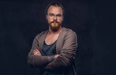 Kızıl saçlı hippi erkek portresi ile gözlük ve tam sakal, bir stüdyoda Çapraz kollar ile ayakta rahat kıyafetler giymiş. Karanlık bir arka plan üzerinde izole.