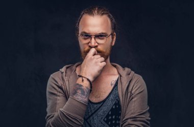 Akıllı dalgın Kızıl saçlı hippi tam sakal ve gözlük ile rahat kıyafetler, çene bir stüdyoda el ile poz giyinmiş. Koyu arka plan üzerinde izole.