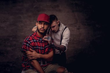 Yakışıklı sakallı Afrikalı-Amerikalı adam bir polar gömlek ve bir saç kesimi eski moda bir profesyonel kuaför tarafından getting kap bir saç kesimi yapıyor.