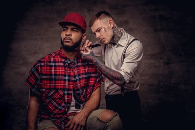 Sakallı Afro-Amerikan hipster adam bir polar gömlek ve bir saç kesimi eski moda bir profesyonel kuaför tarafından getting kap saç kesimi yapıyor.