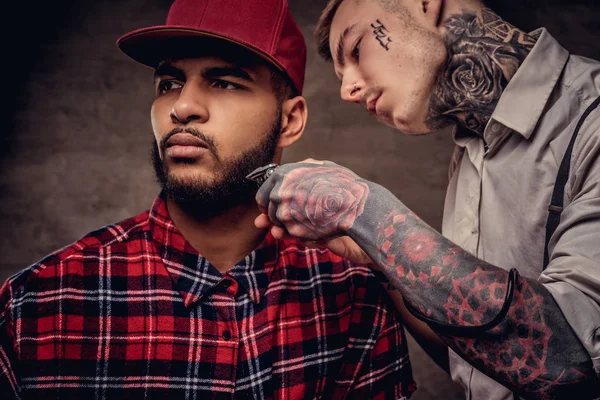 Sakallı Afro-Amerikan hipster adam bir polar gömlek ve bir saç kesimi eski moda bir profesyonel kuaför tarafından getting kap saç kesimi yapıyor.