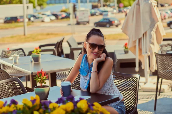 トレンディな服を着て幸せの魅力的なブルネットの少女は屋外カフェのテラスに座って夏の日を楽しんでいます — ストック写真