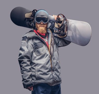 Bir snowboard portresi extream snowboard snowboard yaparken omzunda bir stüdyoda ile poz tam koruyucu giysiler giymiş. Gri bir arka plan üzerinde izole.