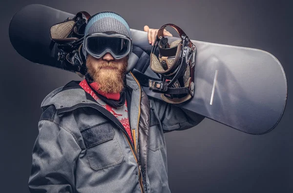 Bir snowboard portresi extream snowboard snowboard yaparken omzunda bir stüdyoda ile poz tam koruyucu giysiler giymiş. Gri bir arka plan üzerinde izole.