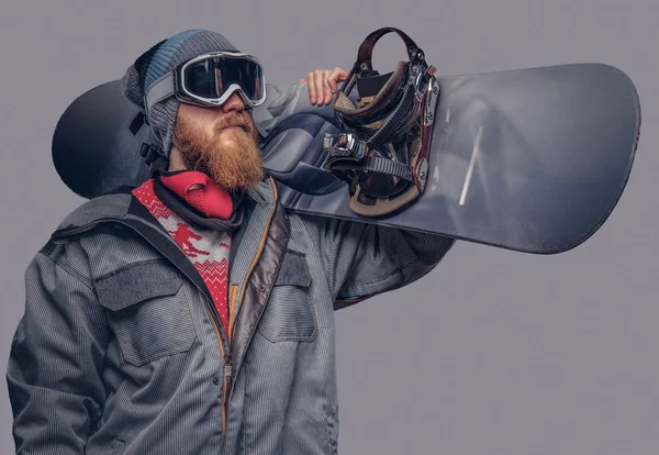 Bir snowboard portresi extream snowboard snowboard yaparken omzunda bir stüdyoda ile poz tam koruyucu giysiler giymiş. Gri bir arka plan üzerinde izole.