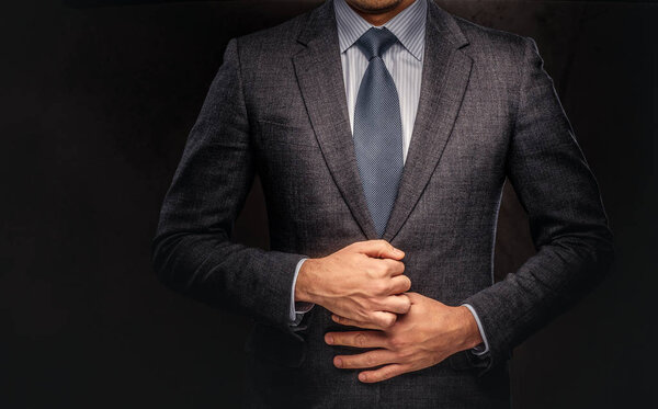 Cropped portrait of a successful businessman buttoning his elegant suit. Isolated on a dark background.