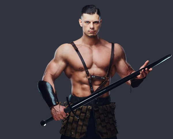 野蛮的古希腊战士与肌肉的身体在一个黑暗的背景下的战斗制服摆出 — 图库照片